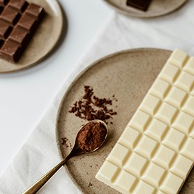 Tablettes de chocolat sur des assiettes et poudre de cacao dans une cuieillere à café